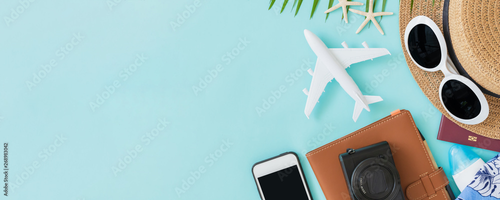Top view of traveler accessories, tropical palm leaf and airplane on blue background with empty space for text. Travel summer holiday vacation banner concept. - obrazy, fototapety, plakaty 