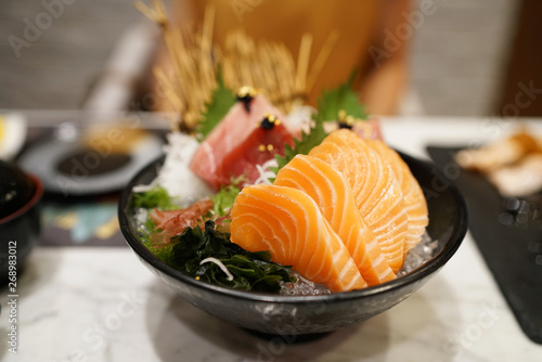 Salmon sashimi - Raw fresh salmon sliced and tuna (otoro, chutoro, akami) served on black plate with wasabi and shredded radish, Traditional Japanese food.