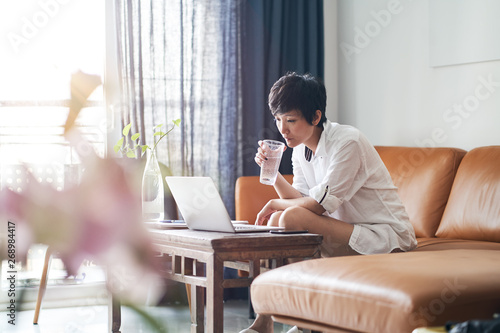Asian woman working on laptop from home as freelancer