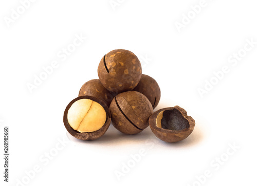 Pile of macadamia nuts with sawn nutshell and isolated on white background