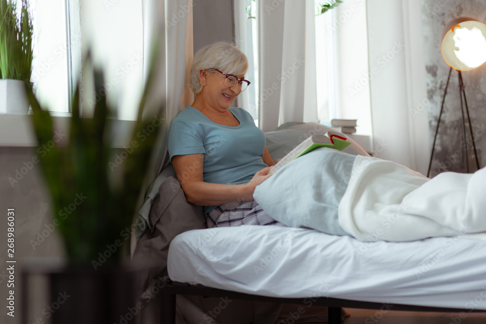 Charming lady lying in the bed and enjoying books reading. Charming lady lying in the bed and enjoying books reading.