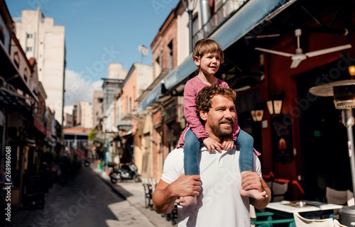 Father with small daughter standing outdoors in mediterranean town.