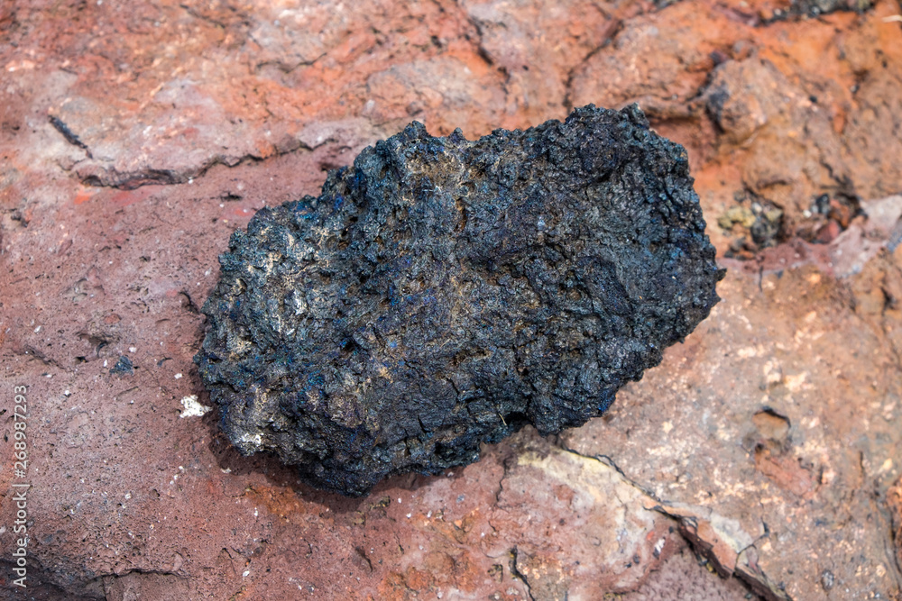 Naklejka premium Black lava rock from volcano on a pumice background.