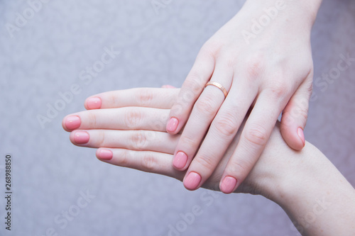 Pink solid color manicure on female hands. Gentle manicure. Gel polish. Well-groomed nails.