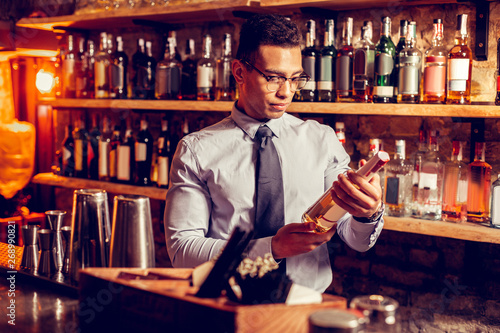 Handsome businessman wearing glasses holding bottle of whisky