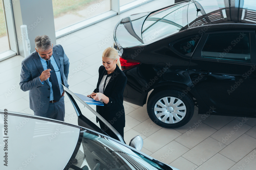 sales agent showing vehicles to a customer in car showroom