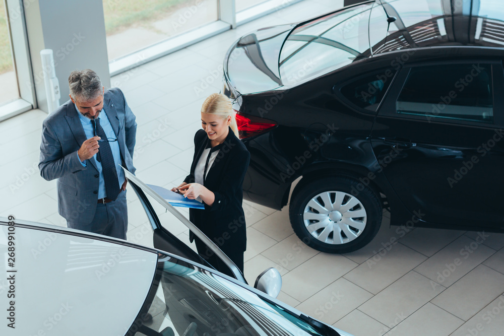sales agent showing vehicles to a customer in car showroom sales agent showing vehicles to a customer in car showroom