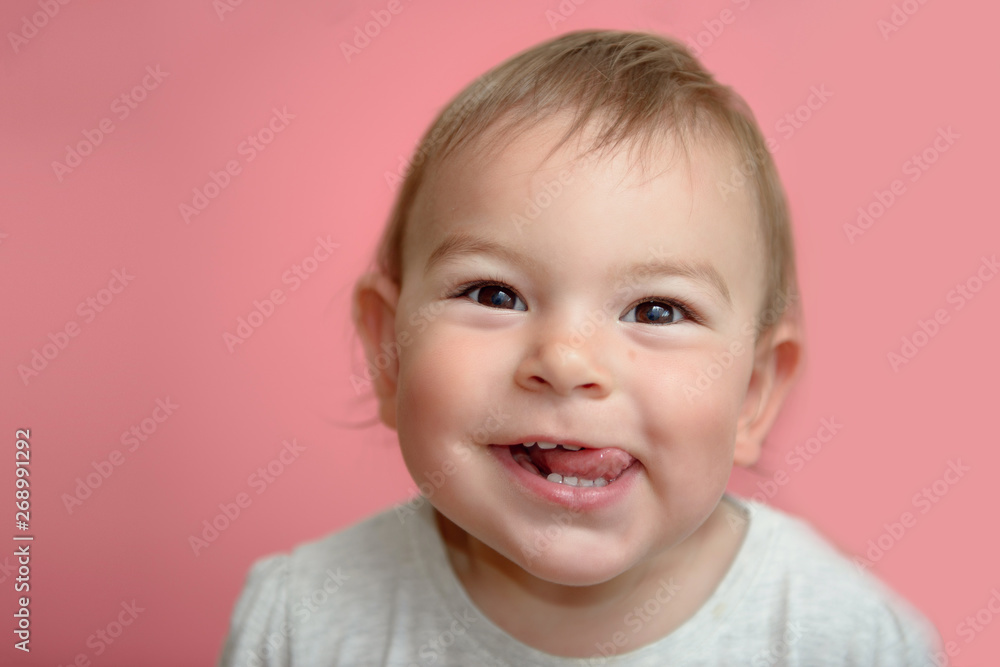 Cute happy funny baby toddler face smiling showing teeth and tounge, on pink background, happy Cute happy funny baby toddler face smiling showing teeth and tounge, on pink background, happy