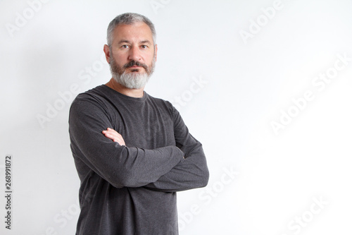 Half-length portrait of a serious gray-haired bearded man in a gray t-shirt on a white background