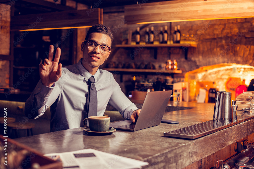 Businessman calling for barman after working on laptop Businessman calling for barman after working on laptop