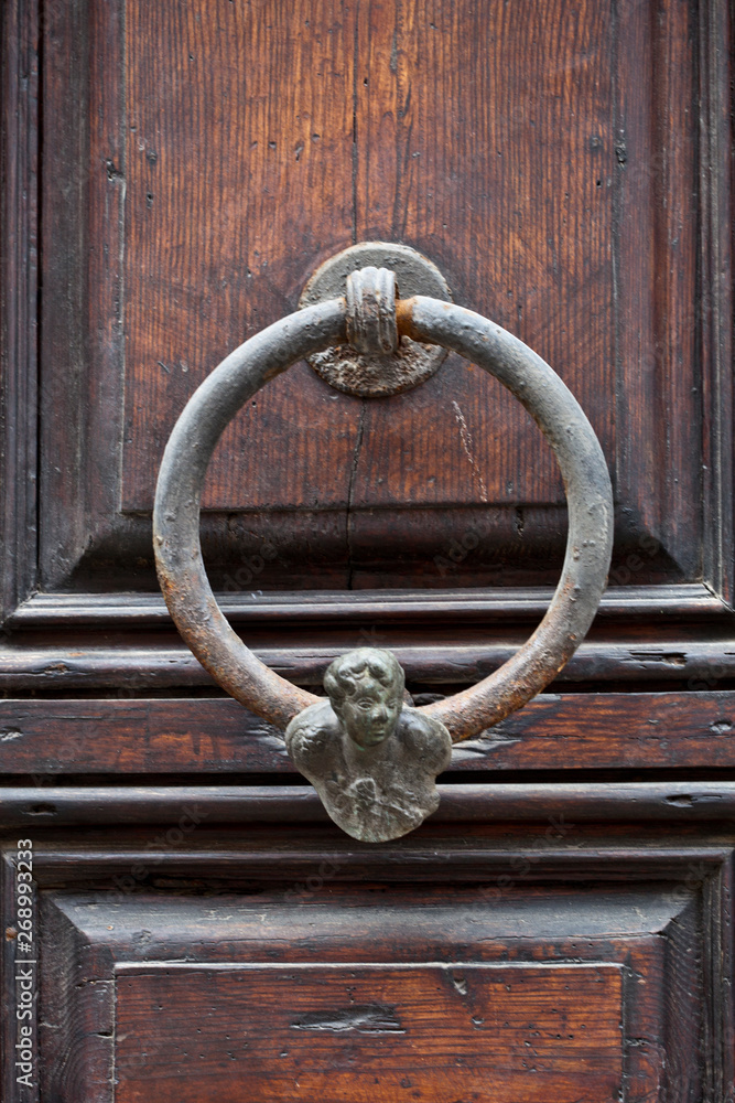 Ancient italian door knocker on wooden brown door. Ancient italian door knocker on wooden brown door.