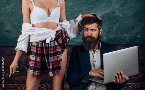 Sex education. Sex role game. Guy laptop erotic video. Man experienced  bearded teacher and seductive female sexy boobs. Learning sexy female body.  Sexual life concept. Desirable student sexy breasts Stock Photo