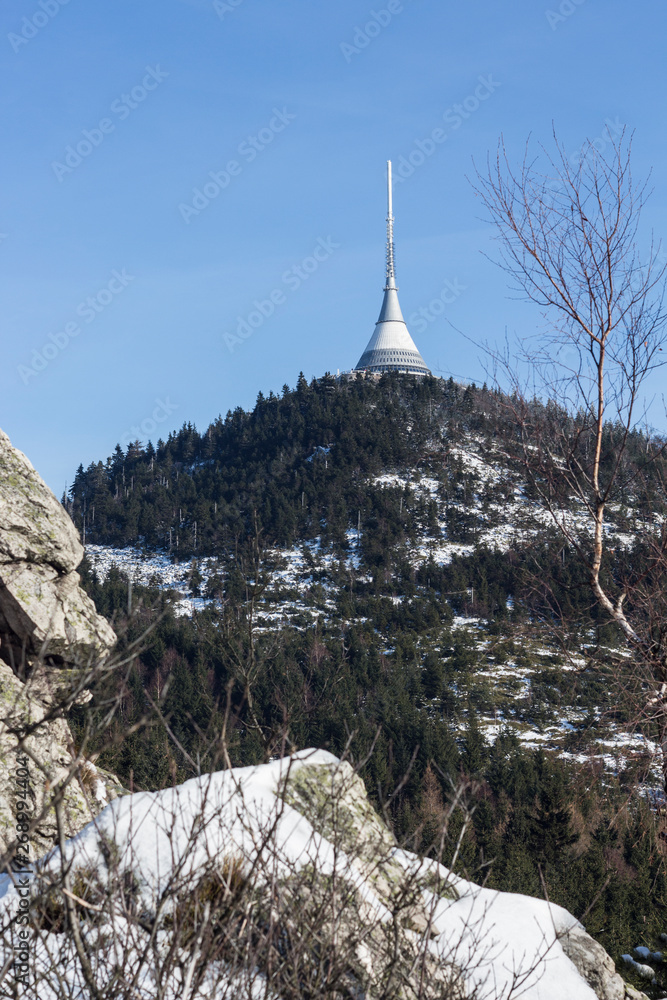 Winter view of a landscape of Jizerske mountains and the top of Jested mountain. Rocks, forest and blue sky over the Jested summit, snow on the ground. Winter view of a landscape of Jizerske mountains and the top of Jested mountain. Rocks, forest and blue sky over the Jested summit, snow on the ground.