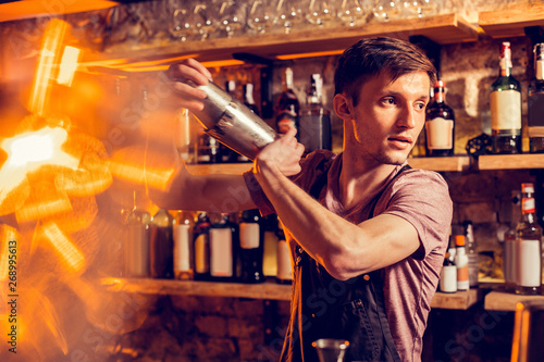 Young but experienced barman making cocktail for client photo