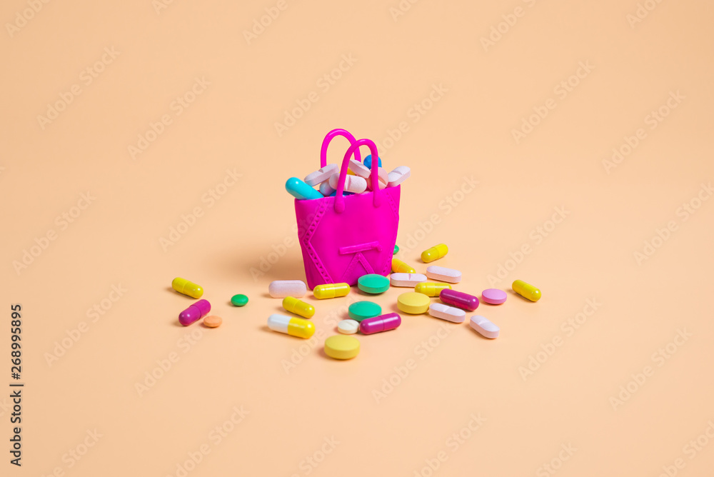 Colored pills fall out of a pink handbag on an orange background