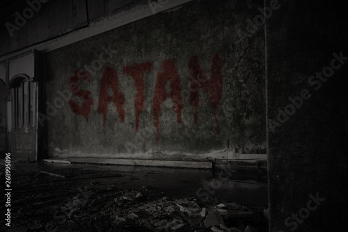 text satan on the dirty wall in an abandoned ruined house photo