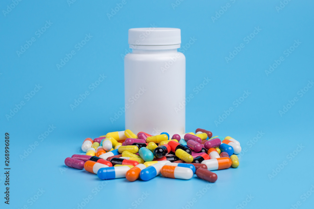 Medicine green, yellow and pink pills or capsules and white bottle Medicine green, yellow and pink pills or capsules and white bottle
