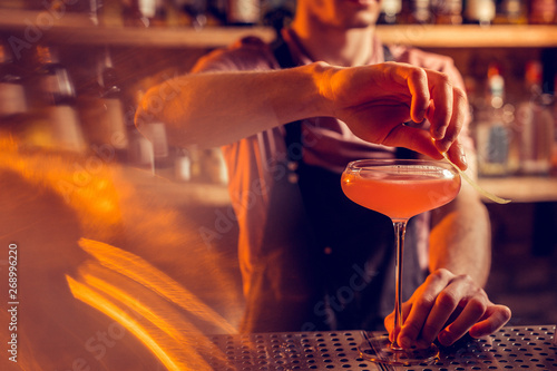 Close up of barman finishing making cocktail for client