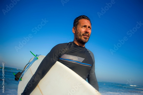 Photography lifestyle portrait of attractive and cool surfer man 3os to 40s in neoprene surf