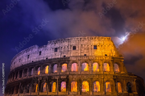 Dettaglio del Colosseo di notte con la luna piena e finestre infuocate