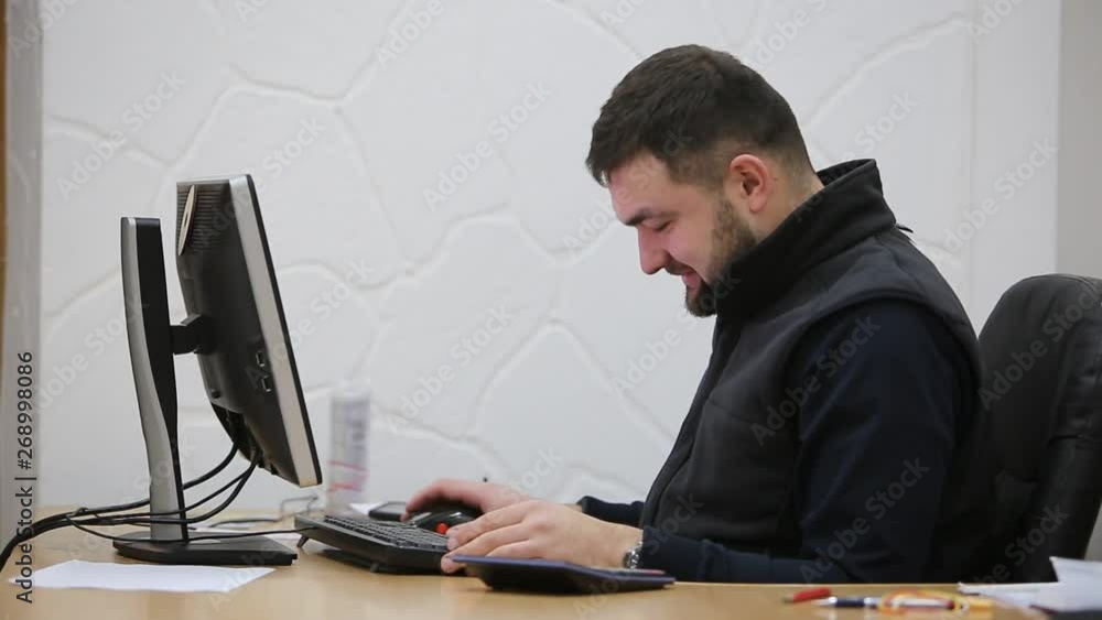 Young bearded office worker man working behind desk on computer. Young bearded office worker man working behind desk on computer.