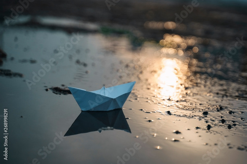 Paper boat on beach on sunset time