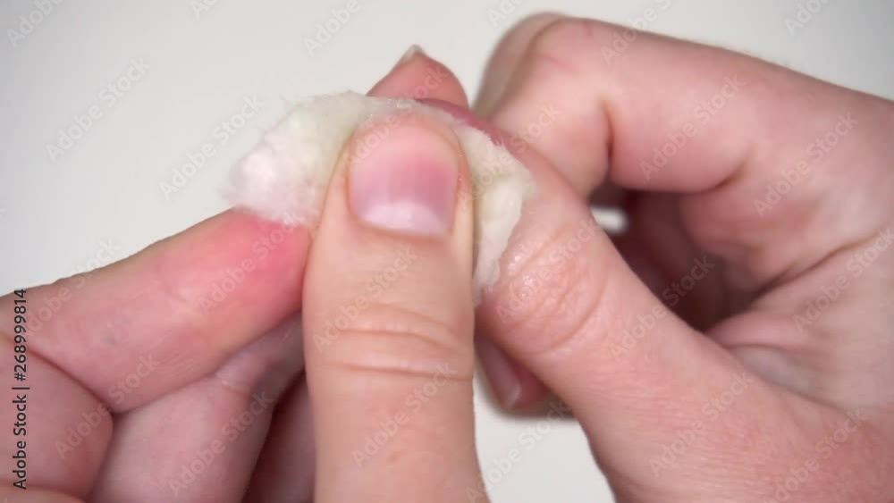 woman doing manicure hands care washes nail polish with a cotton pad on a white background and looks at the result close-up woman doing manicure hands care washes nail polish with a cotton pad on a white background and looks at the result close-up