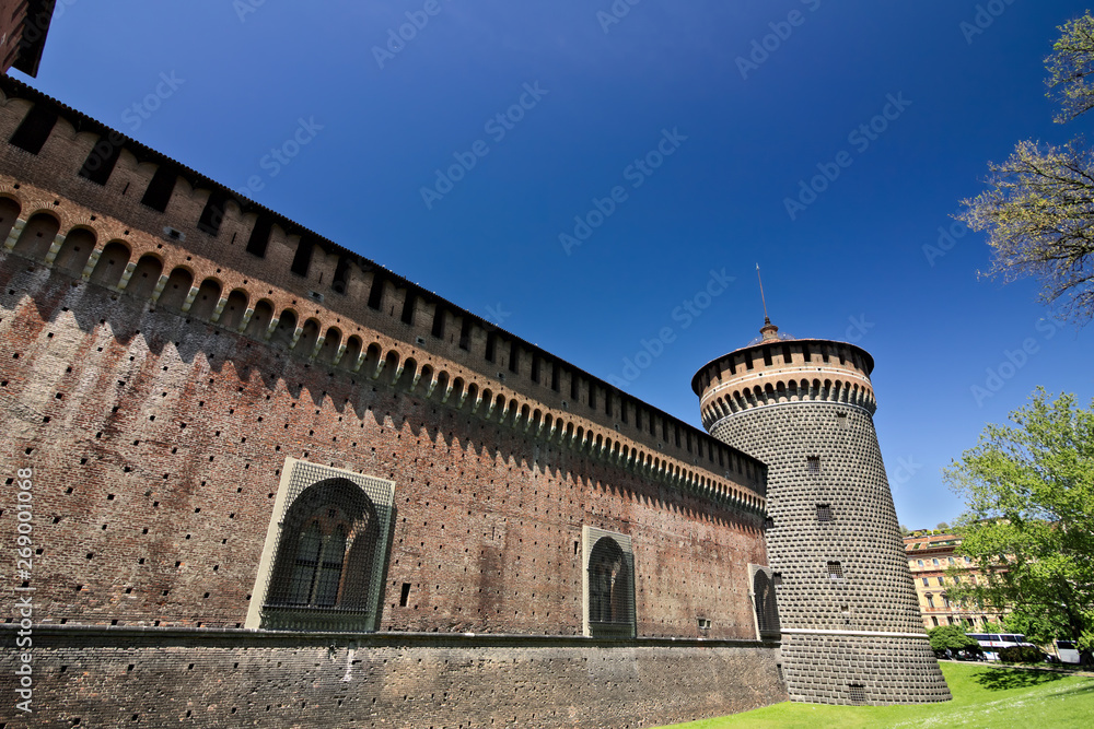 Sforza Castle in Milan. Cylindrical tower and walls. The Castle with the walls and the background of the blue sky of a spring day.