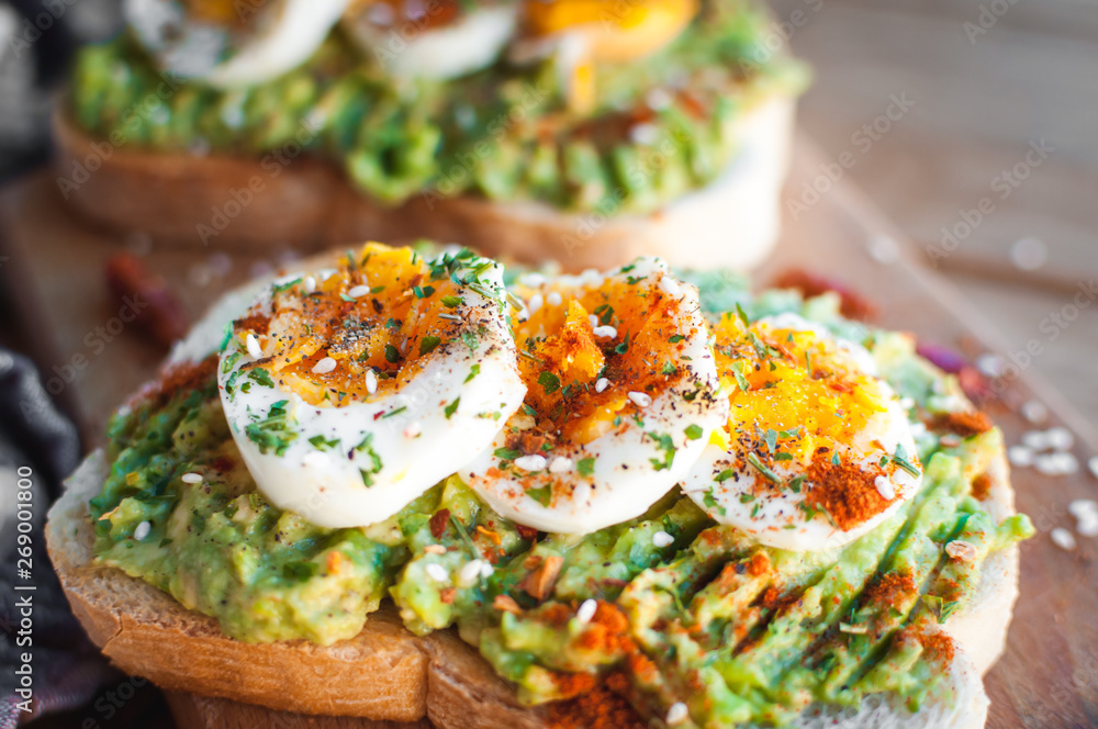 Close-up of avocado and egg toast with herbs and seasonings, on cutting board Close-up of avocado and egg toast with herbs and seasonings, on cutting board