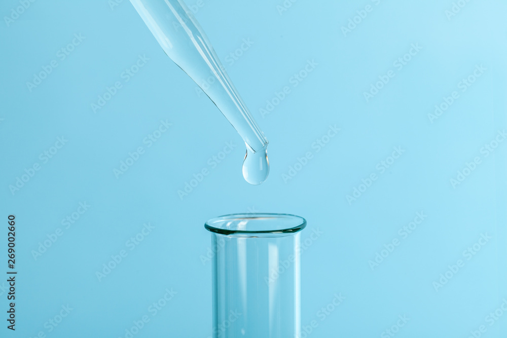Drop the pipette into the test tube. The study of biological material. Laboratory research. Blue background. Drop the pipette into the test tube. The study of biological material. Laboratory research. Blue background.