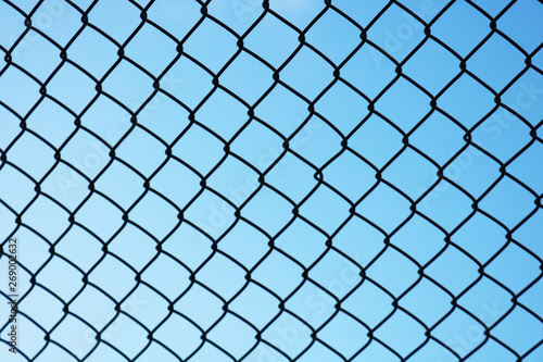 View of blue sky through metal grid. Background of metal mesh