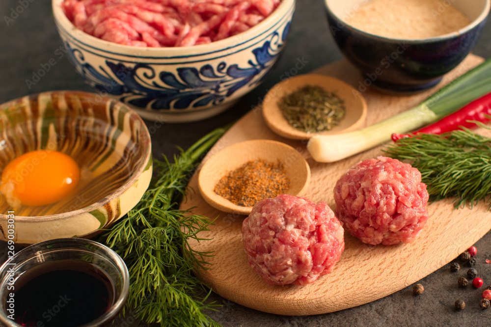 Raw meatballs with fresh ingredients, vegetables and herbs on a table 