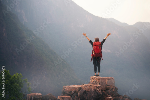 Backpacker woman standing on top of mountain and open arm with nature background