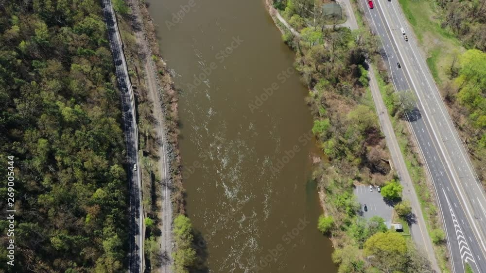 Marvelous drone shot over a murky river next to a highway in a forest area Marvelous drone shot over a murky river next to a highway in a forest area
