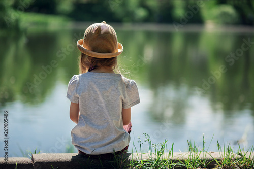 Girl sitting by the lake in the park back view