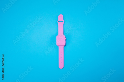 Pink watch lie on pastel blue background. Minimal summer concept.