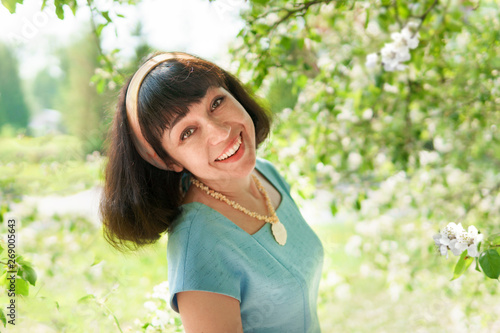 Beautiful woman in a long blue dress with flowering apple trees in the spring garden