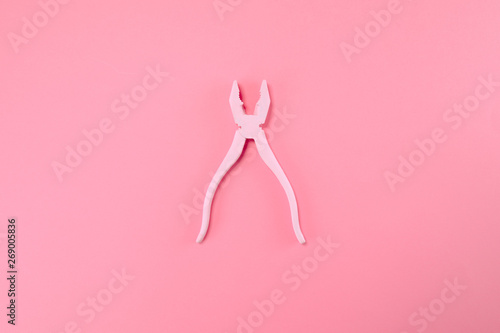 Pink pliers lie on pastel pink background. Minimal summer concept.