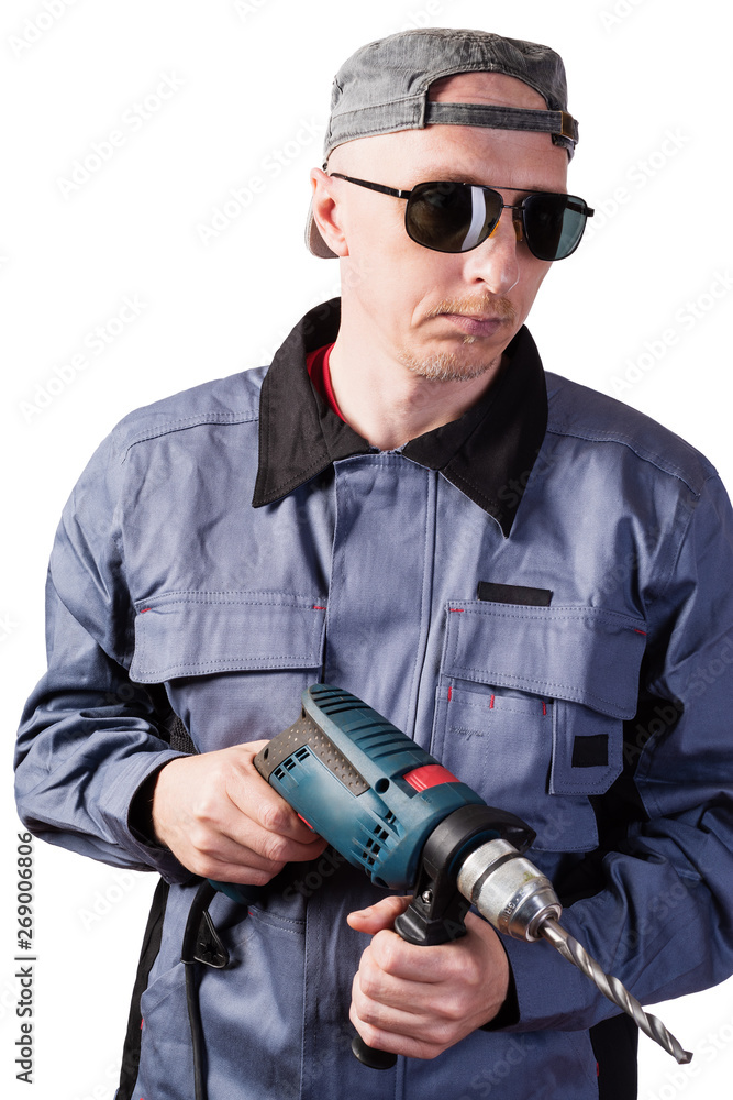 A man in working clothes, dark goggles and a cap, with an electric drill. A man of middle age, European appearance, in a working overalls. Isolated on white background A man in working clothes, dark goggles and a cap, with an electric drill. A man of middle age, European appearance, in a working overalls. Isolated on white background