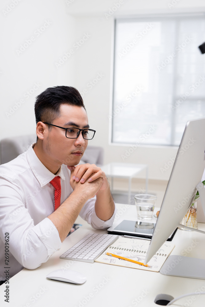 Young stylish worker at office working with computer and thinking how to solve difficult task Young stylish worker at office working with computer and thinking how to solve difficult task