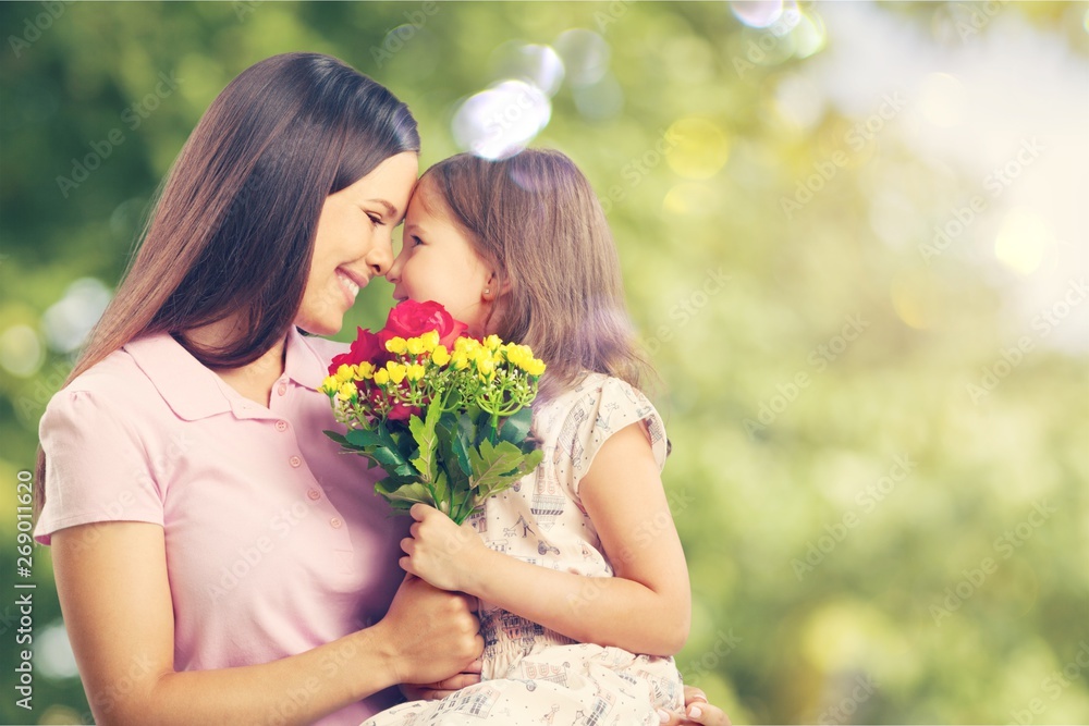 Portrait of happy mother and daughter holding flowers on natural background Portrait of happy mother and daughter holding flowers on natural background