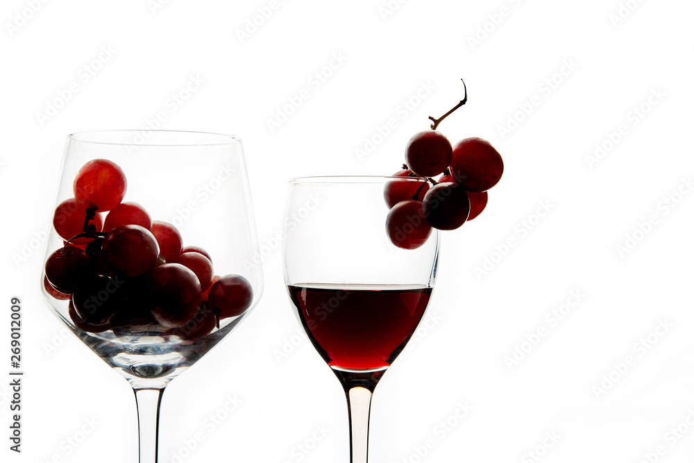 Crystal glasses with red grape and tasty wine on white background Crystal glasses with red grape and tasty wine on white background