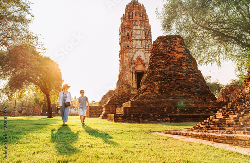 Mother and son tourists walking hand in hand in atcient Wat Chaiwatthanaram Buddhist temple ruines in holy city Ayutthaya, Thailand in Auyttaya