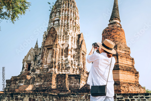 Woman traveler takes a phoot of atcient Wat Chaiwatthanaram Buddhist temple in the city of Ayutthaya Historical Park, Thailand photo