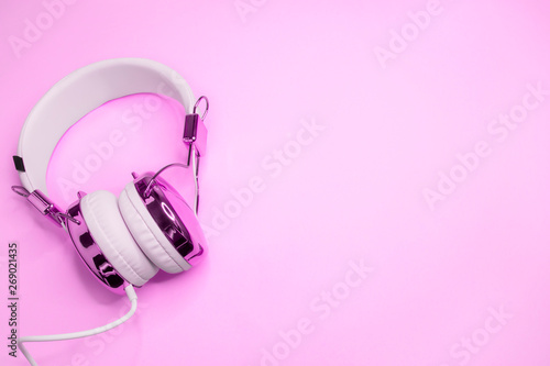 Music design with purple headphones on pink colored background. Minimalist style. An empty space for the text.