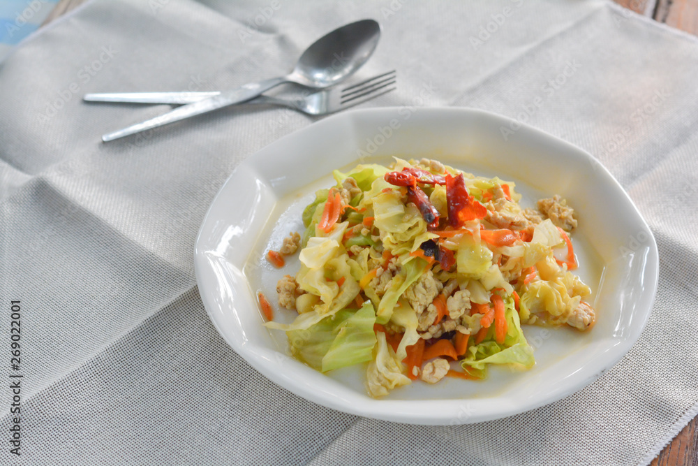 stir fried cabbage with mince chicken breast, red dried chili, slice carrots on white dish for served with rice. Thai delicious food for dinner. stir fried cabbage with mince chicken breast, red dried chili, slice carrots on white dish for served with rice. Thai delicious food for dinner.