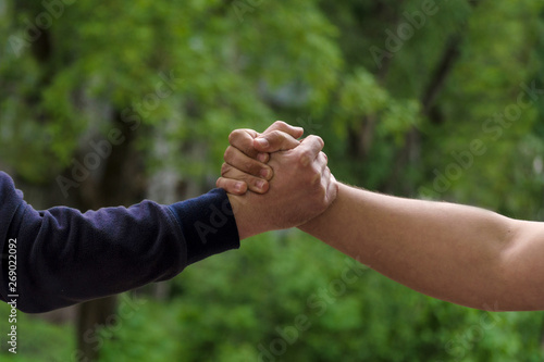 Men shake hands. Businessmen handshaking after good deal. Concept of successful business partnership meeting . Holding hands. Close Up view on green nature background. Minimal composition, copy space © bakulelya