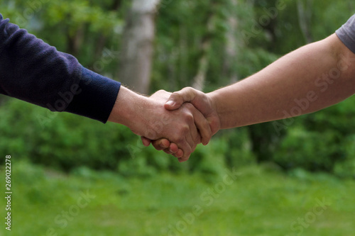 Men shake hands. Businessmen handshaking after good deal. Concept of successful business partnership meeting . Holding hands. Close Up view on green nature background. Minimal composition, copy space