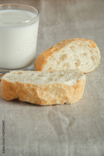 Glass of milk with fresh bread on a tablecloth. 