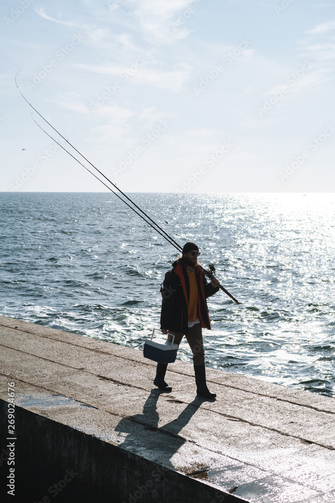 Silhouette of man fisherman wearing coat, holding rod Silhouette of man fisherman wearing coat, holding rod
